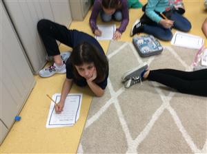 students spread across on floor writing thank you letters to military families 